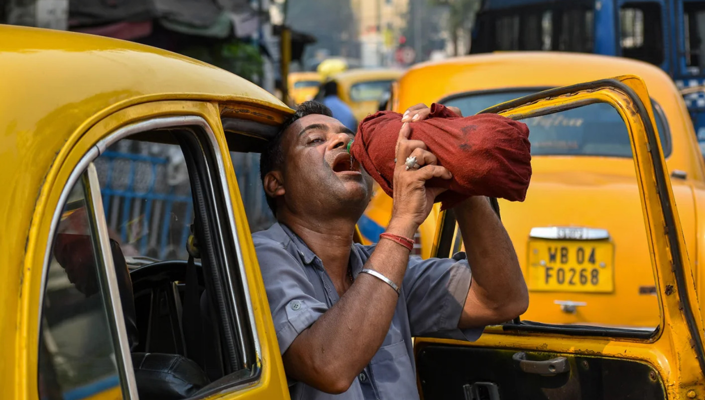 Một tài xế taxi uống nước giải khát giữa cái nắng buổi trưa ở Kolkata, Ấn Độ, vào ngày 18/4. (CNN)