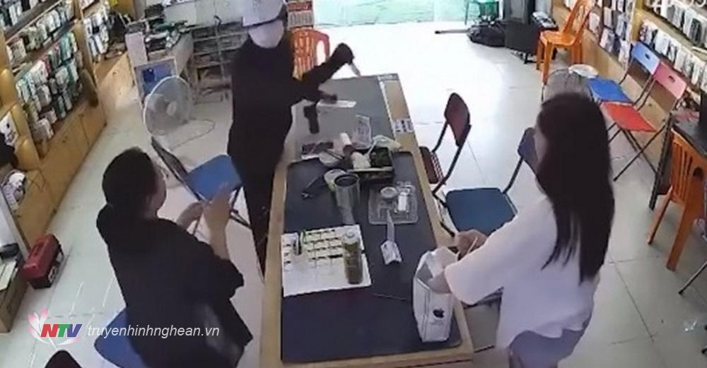 Đối tượng dùng hung khí khống chế nhân viên cửa hàng điện thoại (hình ảnh do camera ghi lại)