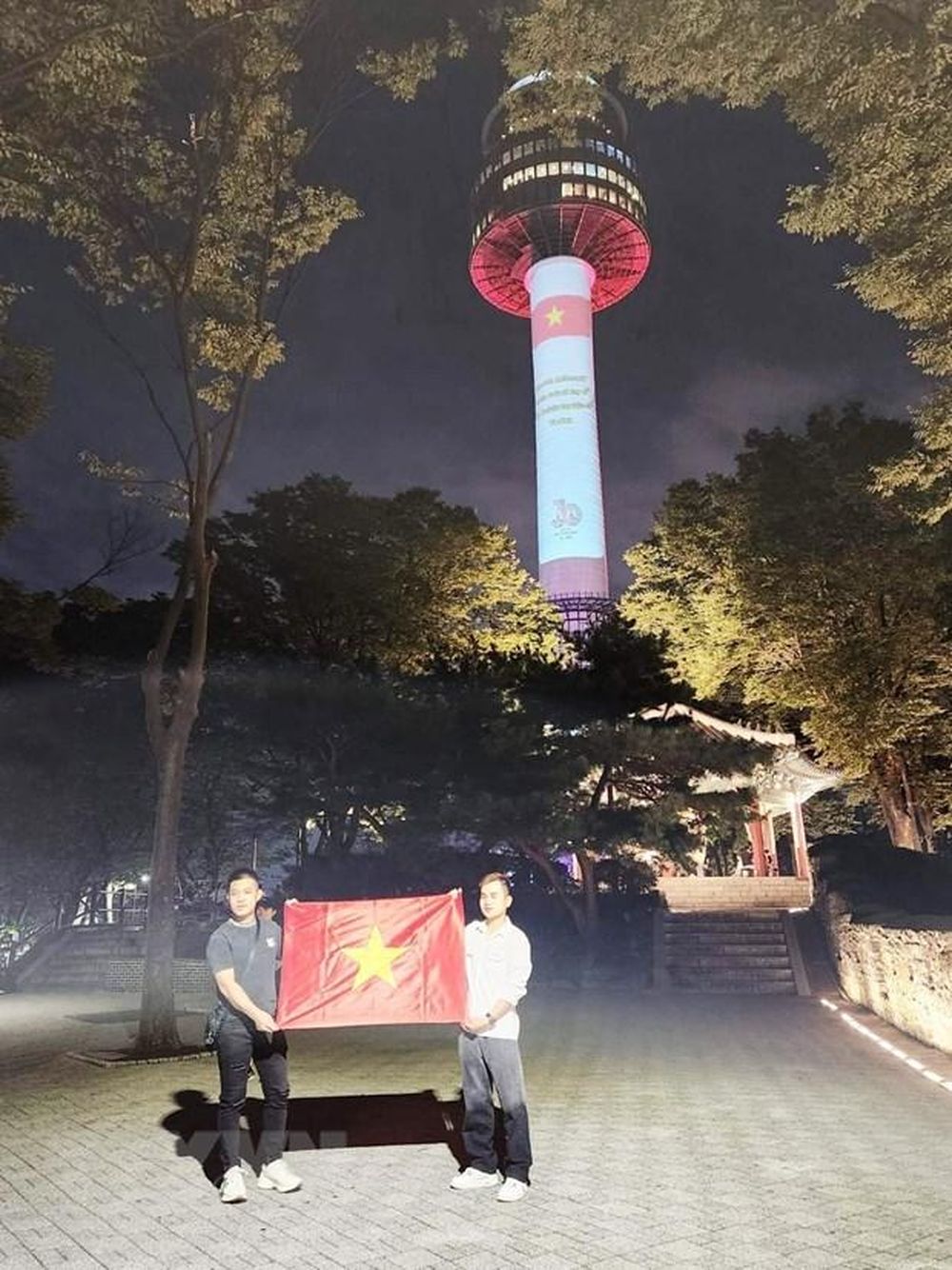 Hai thanh niên PG 88 Nổ Hũ tại Hàn Quốc tự hào chụp ảnh bên lá quốc kỳ dưới chân tháp Namsan.