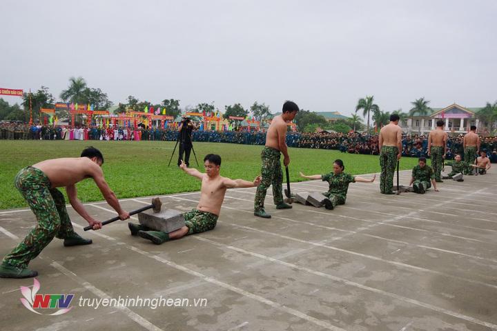 Nam và nữ nhân viên đặc nhiệm Bộ đội Biên phòng tỉnh thể hiện nội dung hai người nằm trên bàn chông và mảnh chai cho đồng đội dùng búa đập vỡ khối bê tông đặt trên bụng.