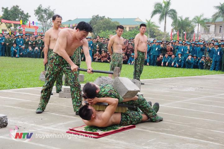 Nam và nữ nhân viên đặc nhiệm Bộ đội Biên phòng tỉnh thể hiện nội dung hai người nằm trên bàn chông và mảnh chai cho đồng đội dùng búa đập vỡ khối bê tông đặt trên bụng