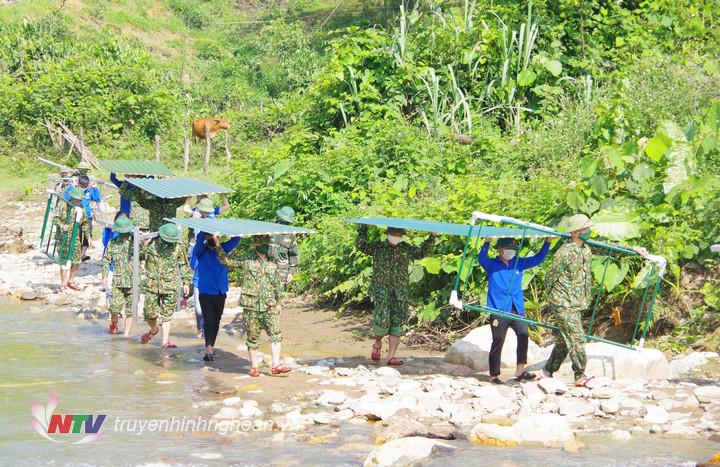 Bộ đội và đoàn viên thanh niên địa phương vượt suối vận chuyển vật liệu xây dựng chốt 