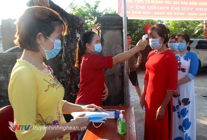 Kiểm tra thân nhiệt, phát khẩu trang... cho cử tri tại điểm bỏ phiếu.