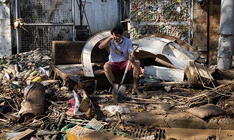 Người đàn ông bật khóc khi dọn dẹp bùn đất bên ngoài nhà ở thành phố Marikina sau bão Vamco. Ảnh: Reuters.