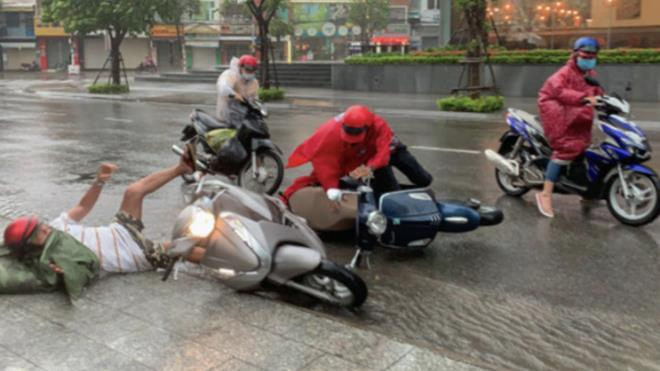 Mưa lớn kèm theo gió mạnh khiến người đi xe máy bị quật ngã xuống đường.
