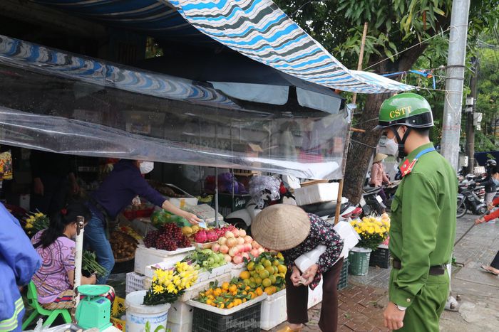 Lực lượng công an nhắc nhở các tiểu thương ở chợ giữ khoảng cách đảm bảo an toàn